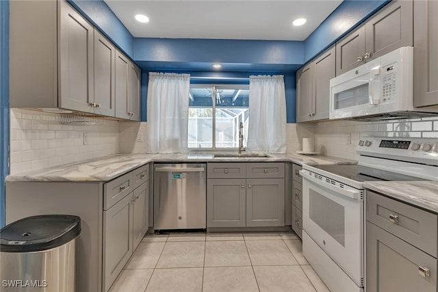 kitchen with gray cabinetry, white appliances, sink, and light tile patterned floors