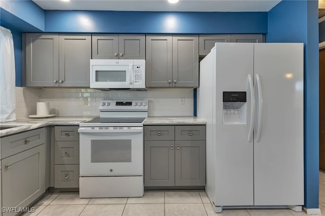 kitchen featuring tasteful backsplash, gray cabinetry, and white appliances