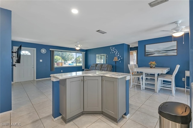 kitchen with gray cabinets, a kitchen island, and light tile patterned floors