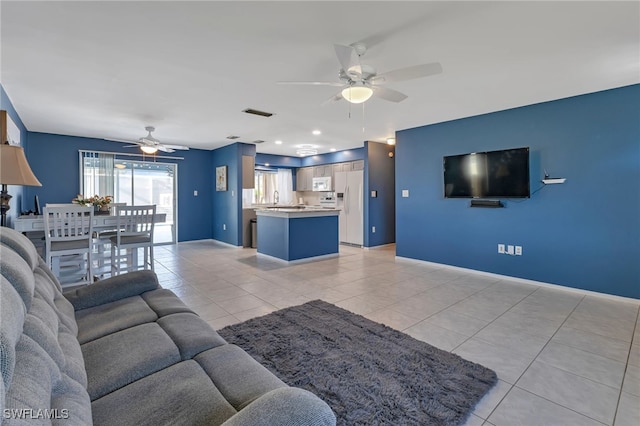 tiled living room with ceiling fan and sink