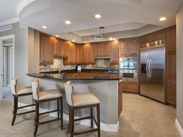 kitchen featuring tasteful backsplash, appliances with stainless steel finishes, sink, kitchen peninsula, and light tile patterned floors