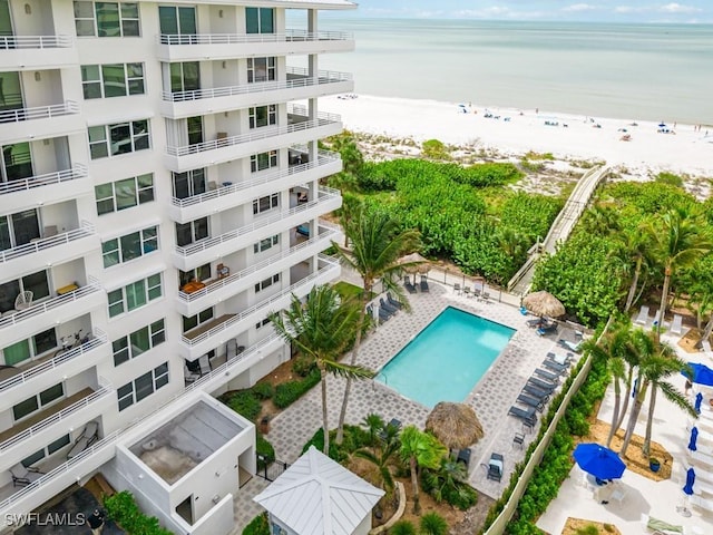 view of swimming pool featuring a patio area, a water view, and a view of the beach