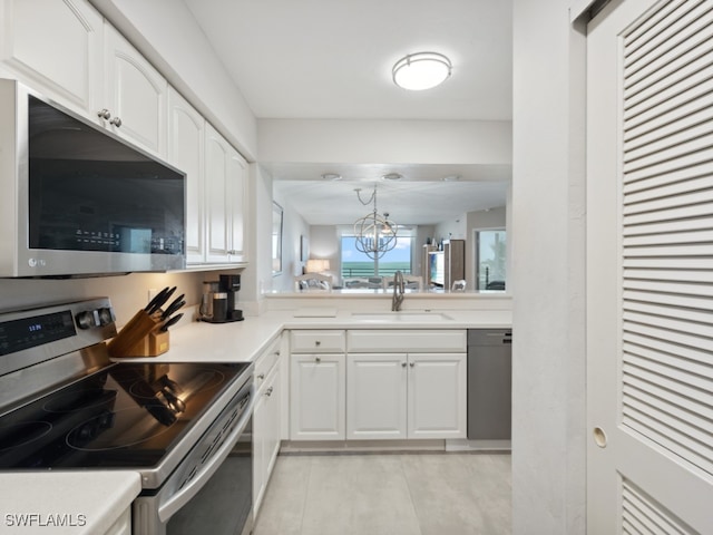 kitchen with white cabinetry, sink, an inviting chandelier, pendant lighting, and appliances with stainless steel finishes