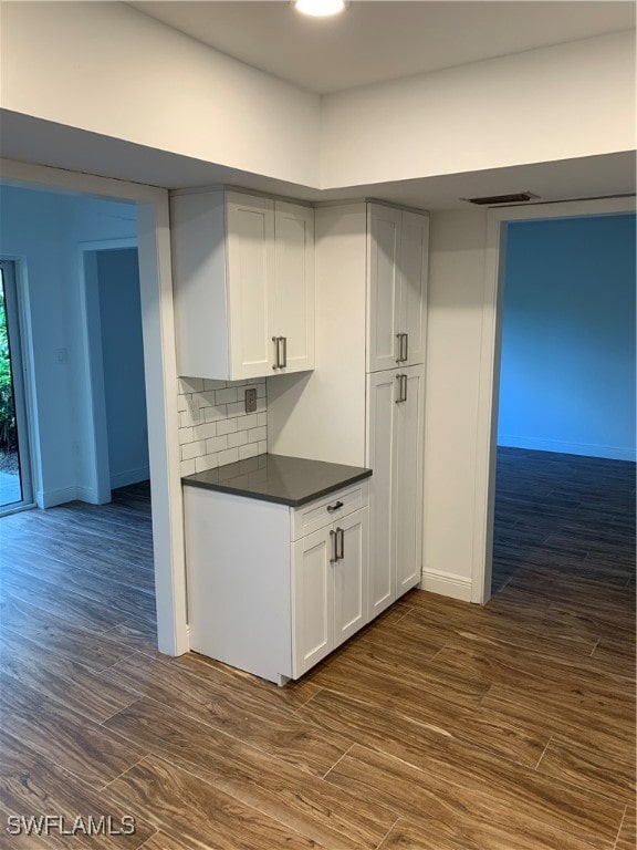 kitchen featuring dark hardwood / wood-style flooring, decorative backsplash, and white cabinets