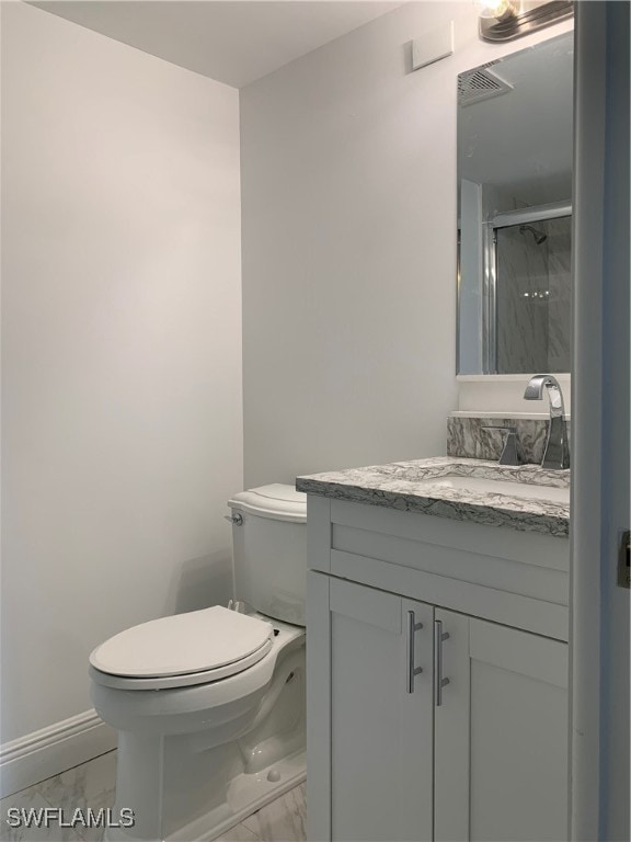 bathroom featuring toilet, vanity, and walk in shower