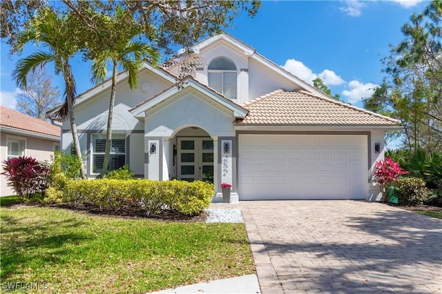 mediterranean / spanish house with a garage and a front lawn