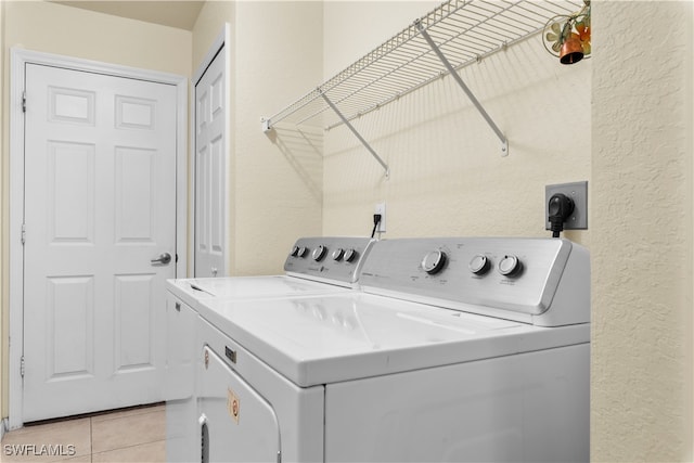 clothes washing area featuring washer and clothes dryer and light tile patterned floors