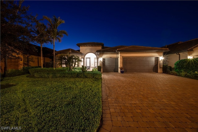 mediterranean / spanish-style house featuring a yard and a garage