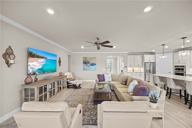 living room featuring light hardwood / wood-style floors, crown molding, sink, and ceiling fan