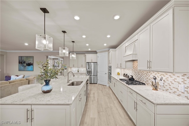 kitchen with custom range hood, stainless steel appliances, sink, pendant lighting, and white cabinets