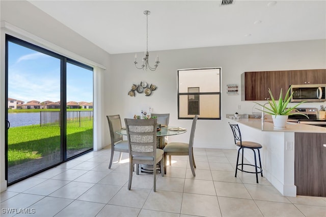 dining space featuring light tile patterned flooring, a water view, and an inviting chandelier