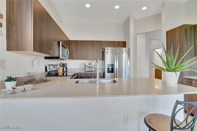 kitchen with appliances with stainless steel finishes, a breakfast bar area, and kitchen peninsula