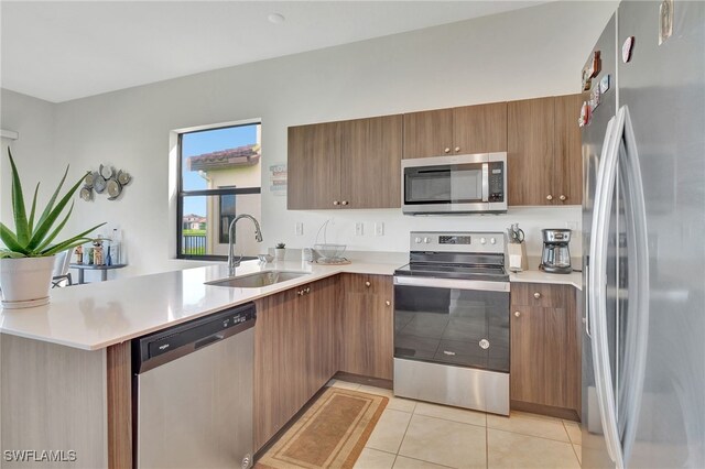 kitchen with sink, appliances with stainless steel finishes, kitchen peninsula, and light tile patterned flooring