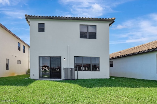 rear view of property with central AC and a yard