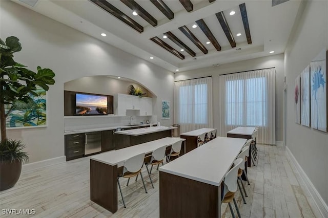 dining area with light hardwood / wood-style flooring, beamed ceiling, and sink