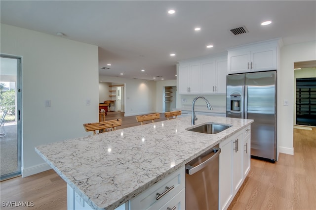 kitchen with sink, white cabinetry, light hardwood / wood-style floors, stainless steel appliances, and a kitchen island with sink