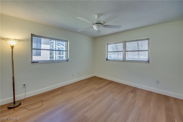 spare room with light wood-type flooring, plenty of natural light, and ceiling fan