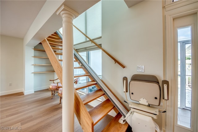 staircase with wood-type flooring and decorative columns