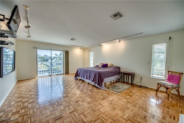 bedroom featuring light parquet flooring, track lighting, multiple windows, and access to outside