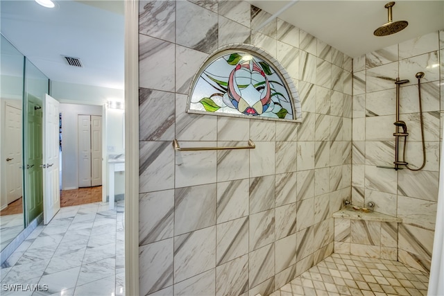 bathroom with a tile shower and vanity