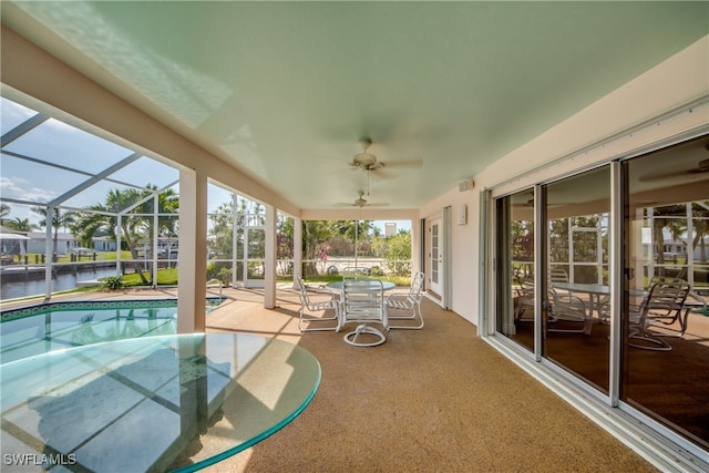 view of swimming pool featuring a patio area, ceiling fan, a water view, and glass enclosure