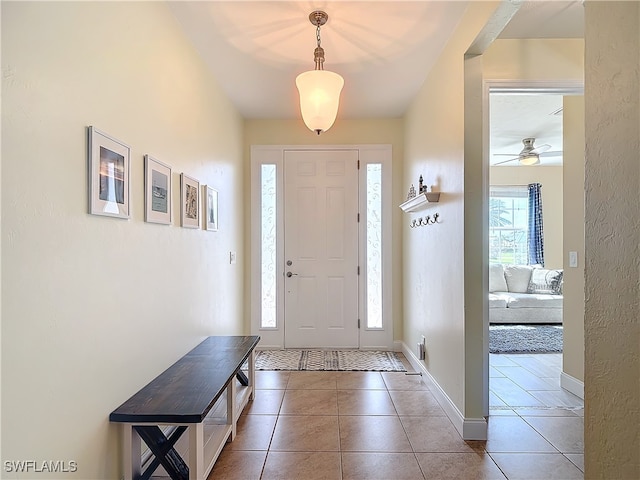 foyer entrance with ceiling fan and dark tile patterned flooring