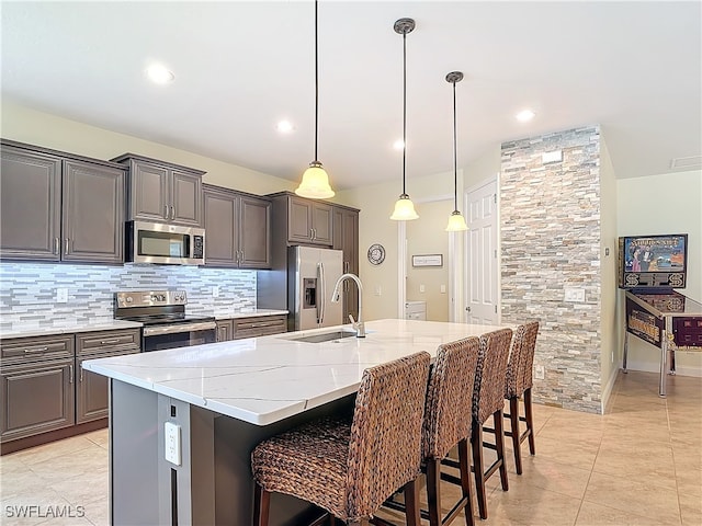 kitchen with a kitchen breakfast bar, stainless steel appliances, a large island, pendant lighting, and light stone counters