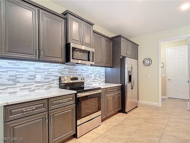 kitchen featuring appliances with stainless steel finishes, decorative backsplash, light stone counters, and light tile patterned floors