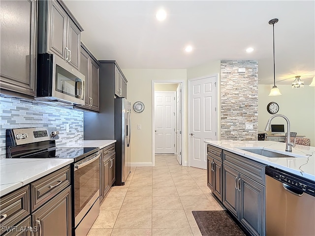 kitchen featuring sink, pendant lighting, light stone counters, and stainless steel appliances