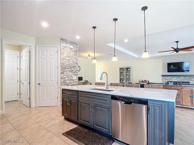 kitchen with dishwasher, a kitchen island with sink, hanging light fixtures, sink, and light stone countertops