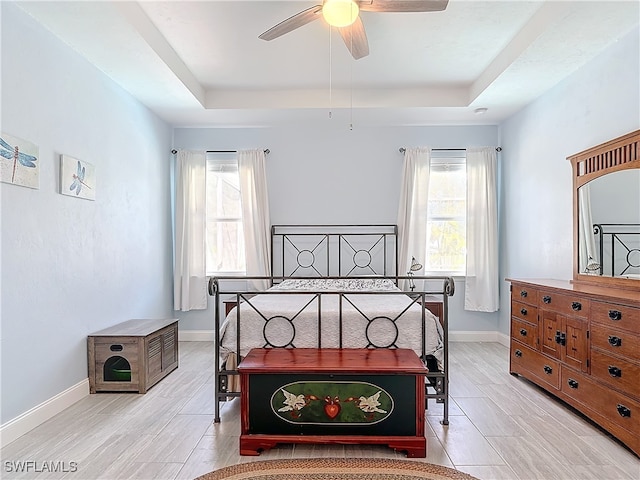 bedroom with a tray ceiling, light hardwood / wood-style floors, and ceiling fan