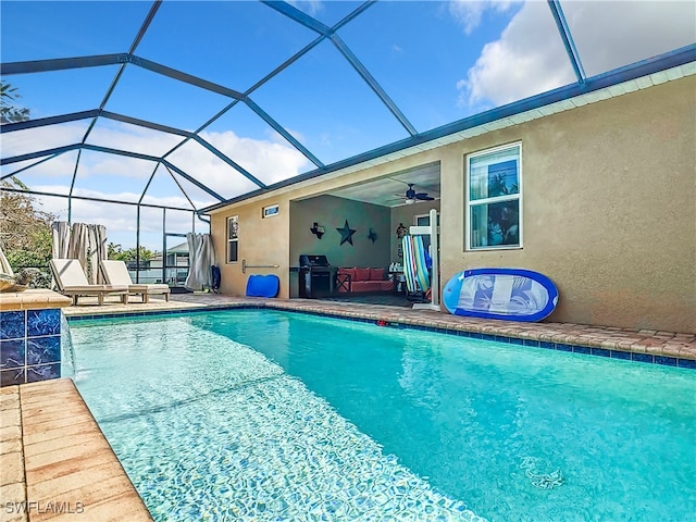 view of swimming pool featuring a patio, pool water feature, a lanai, and ceiling fan