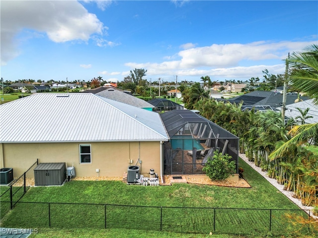 back of house featuring central air condition unit, a storage shed, a lanai, and a yard