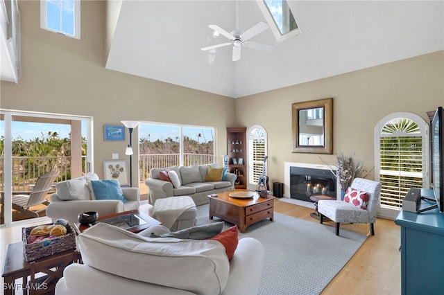 living room featuring a high ceiling, light hardwood / wood-style flooring, and ceiling fan