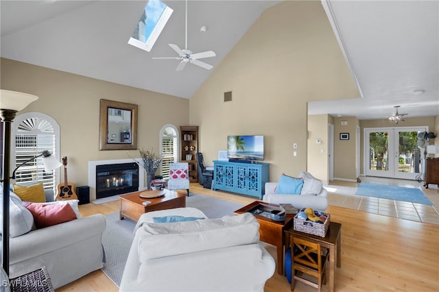 living room featuring a skylight, ceiling fan, light hardwood / wood-style flooring, and a wealth of natural light