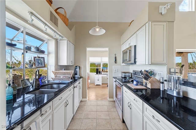 kitchen with white cabinets, appliances with stainless steel finishes, and dark stone countertops