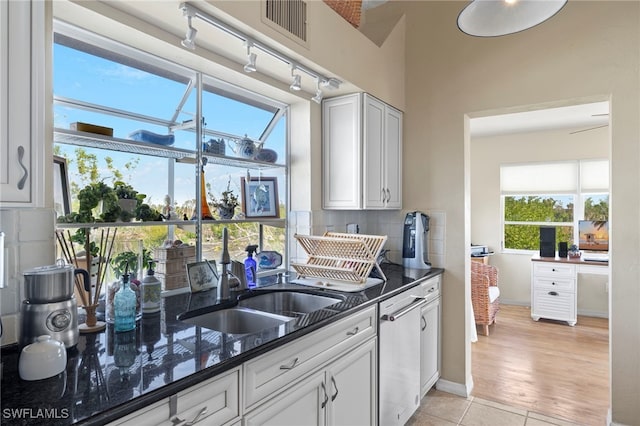 kitchen featuring dark stone counters, sink, tasteful backsplash, light tile patterned flooring, and white cabinetry