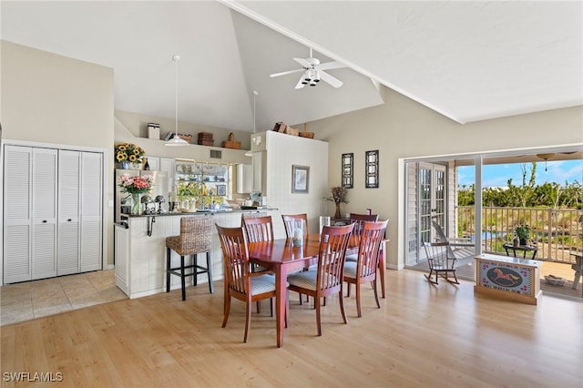 dining room with ceiling fan, high vaulted ceiling, and light hardwood / wood-style floors