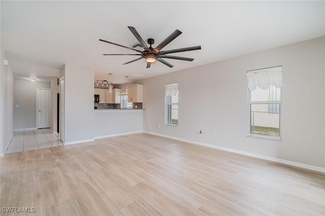 unfurnished living room featuring a wealth of natural light, ceiling fan, and light hardwood / wood-style flooring