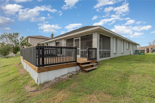 rear view of house featuring a yard, a sunroom, and a wooden deck