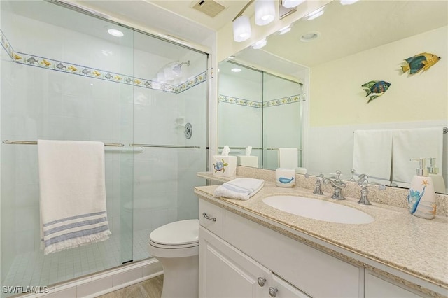 bathroom featuring toilet, vanity, a shower with door, and hardwood / wood-style flooring