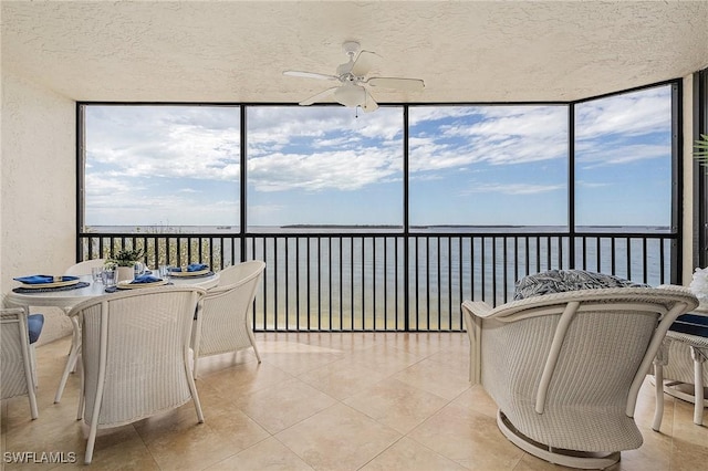 sunroom / solarium featuring ceiling fan and a water view