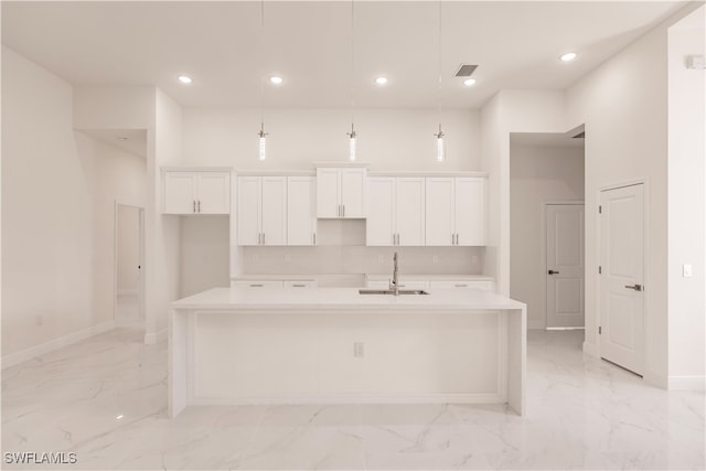 kitchen with white cabinets, a kitchen island with sink, and sink