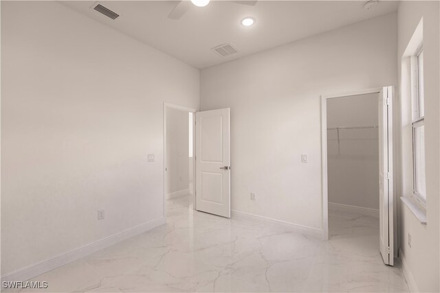 unfurnished bedroom featuring a closet, ceiling fan, and a walk in closet