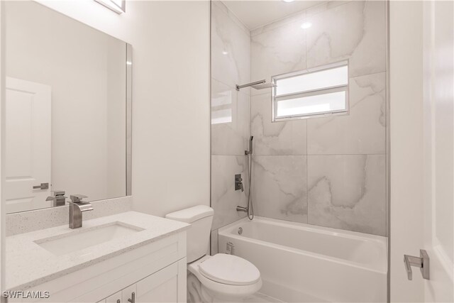 full bathroom featuring tiled shower / bath, vanity, and toilet