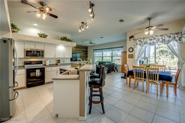 kitchen featuring visible vents, open floor plan, light tile patterned floors, stainless steel appliances, and a sink