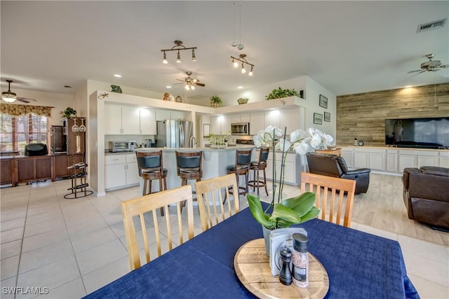 dining space featuring visible vents, wooden walls, a ceiling fan, and a toaster