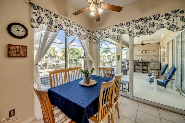 dining room featuring a ceiling fan, a sunroom, light tile patterned flooring, and baseboards