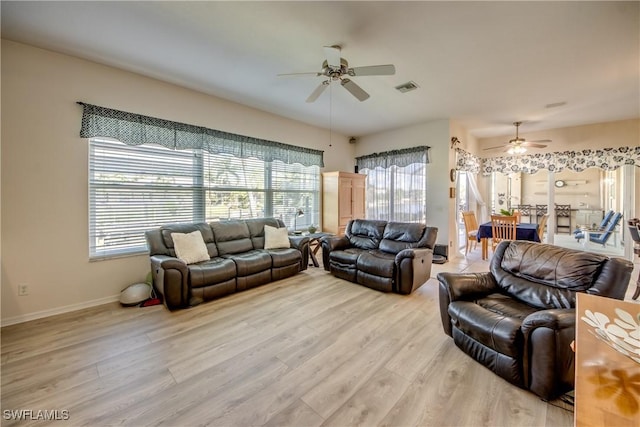 living room featuring light wood finished floors, baseboards, visible vents, and a ceiling fan