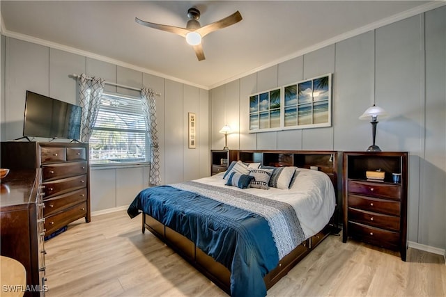 bedroom with crown molding, wood finished floors, a ceiling fan, and a decorative wall